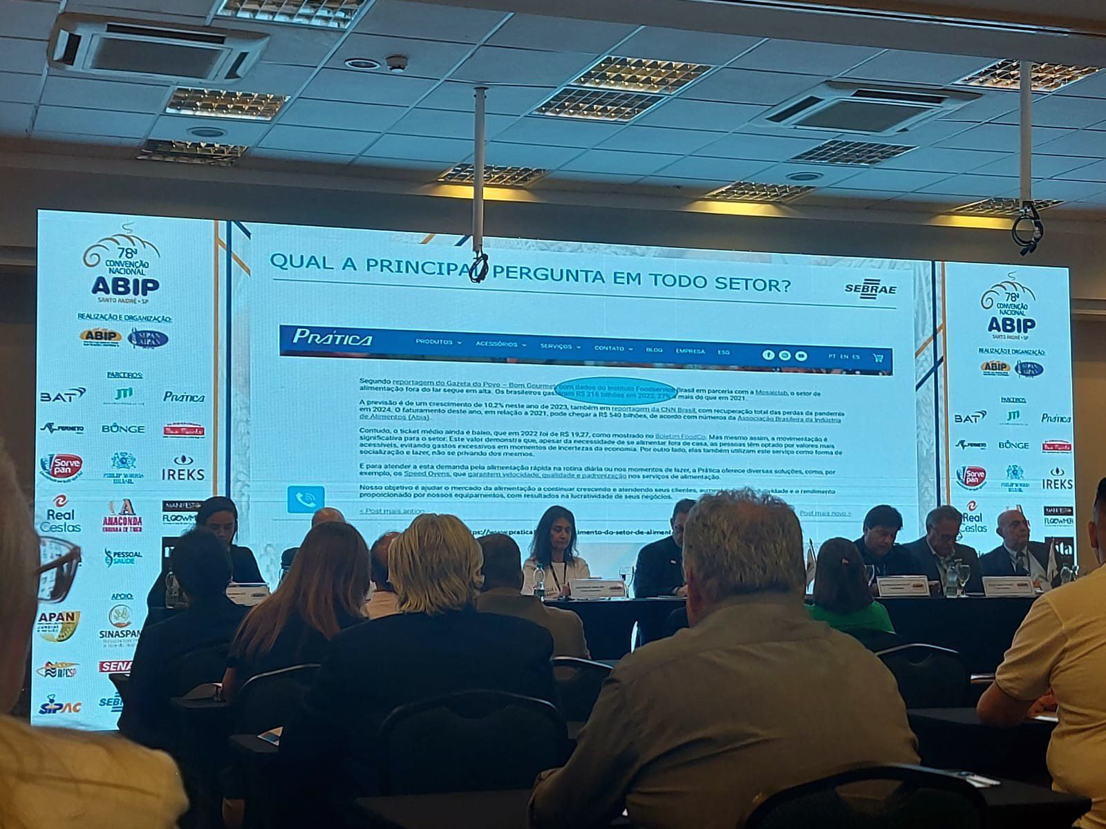 Um grupo de pessoas está sentado em frente a uma tela grande.