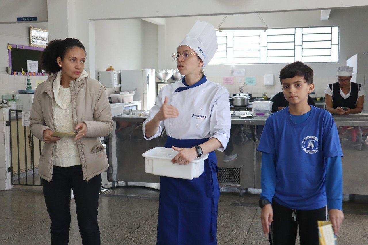 Um grupo de pessoas está em pé na cozinha.
