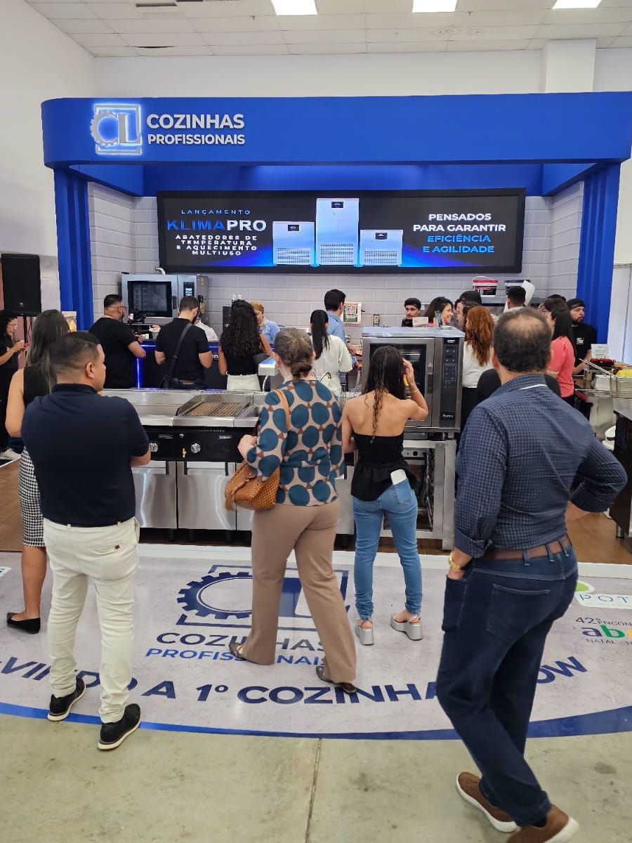 Um grupo de pessoas está em frente a uma vitrine de cozinhas