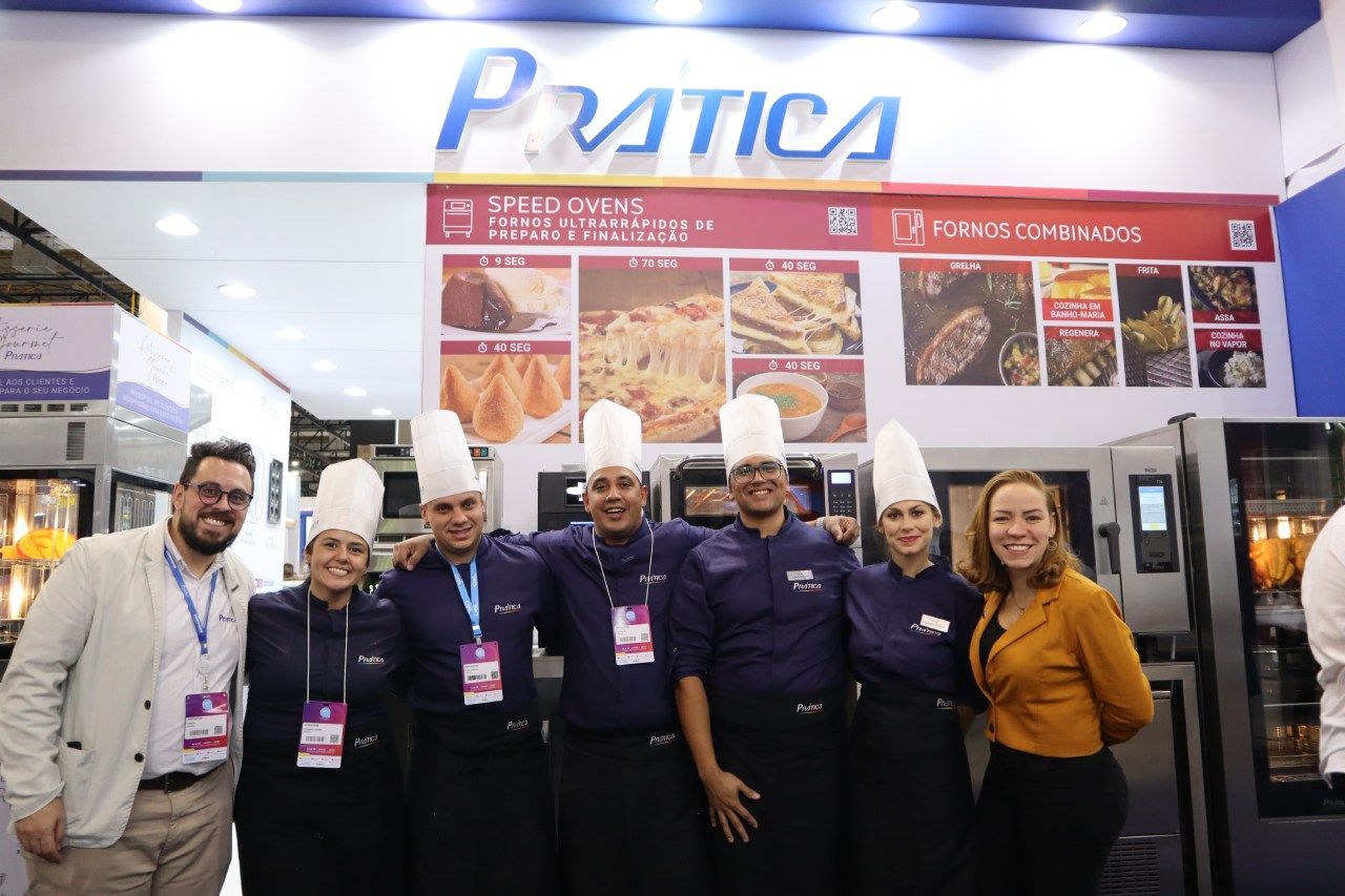 Um grupo de pessoas está posando para uma foto em frente a uma placa de prática.
