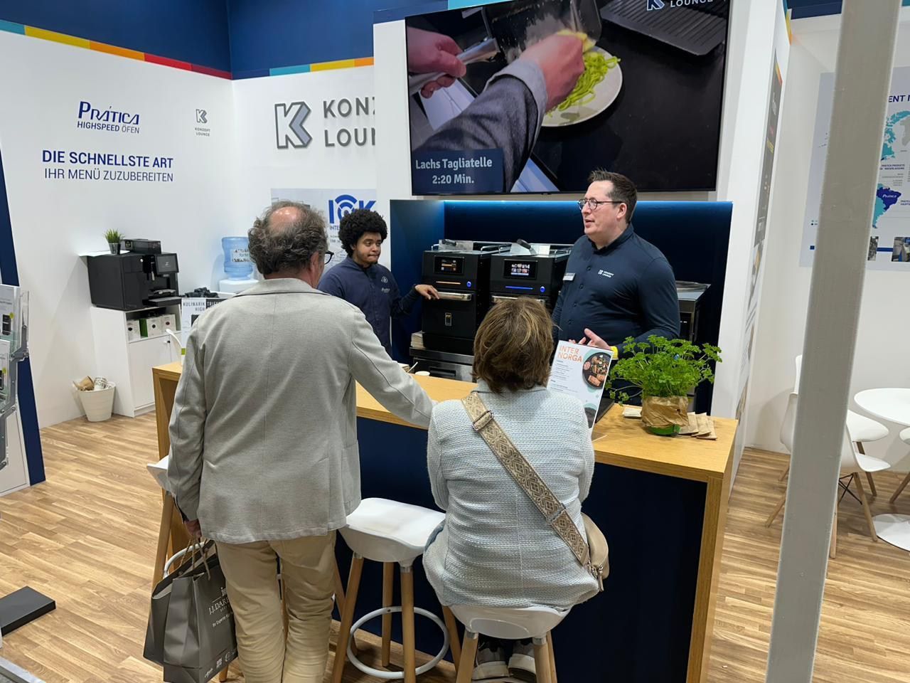 Um grupo de pessoas está em pé ao redor de um balcão em uma sala.