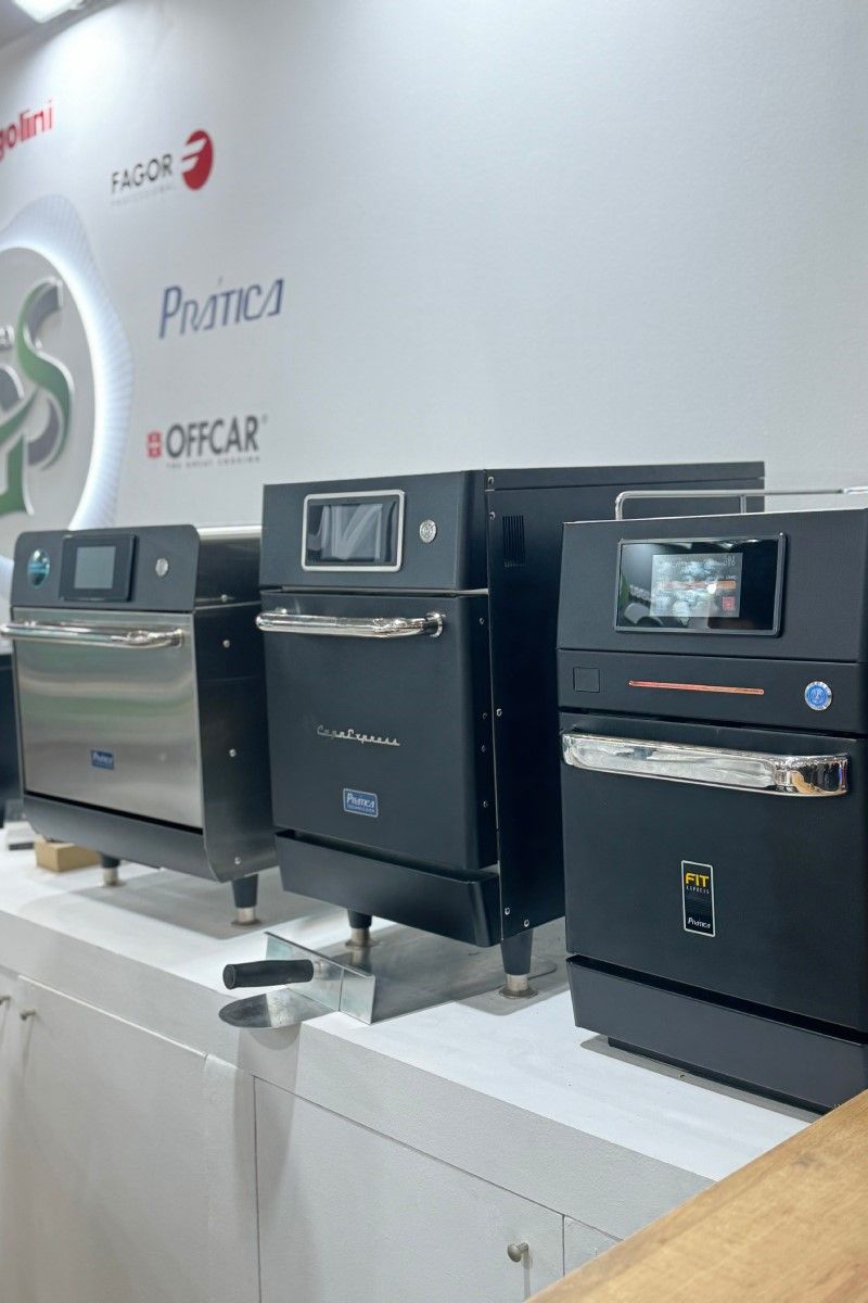 Uma fileira de fornos pretos estão alinhados em uma sala.