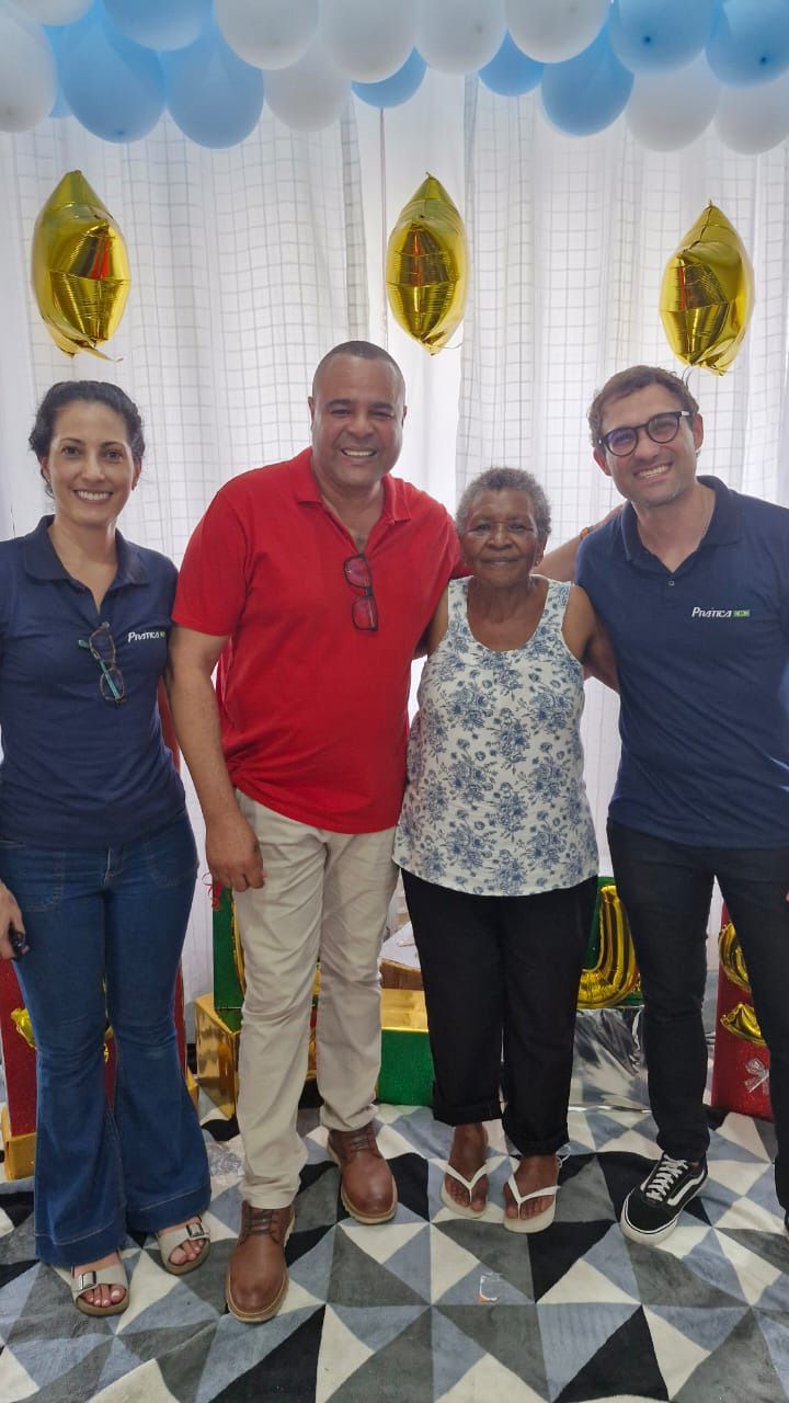 Um grupo de pessoas posando para uma foto com balões ao fundo.