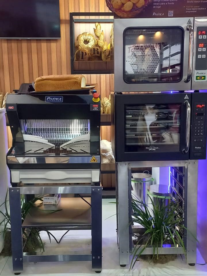 Um fatiador de pão e um forno estão lado a lado em uma padaria.