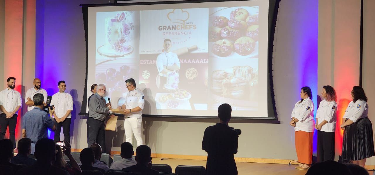 Um grupo de pessoas em pé na frente de uma tela grande.