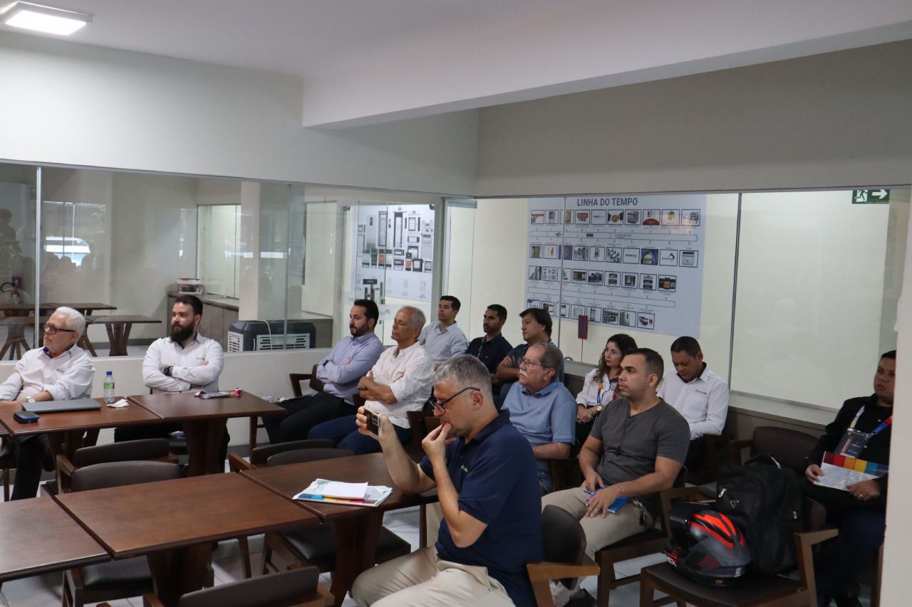 Um grupo de pessoas está sentado em mesas em uma sala.