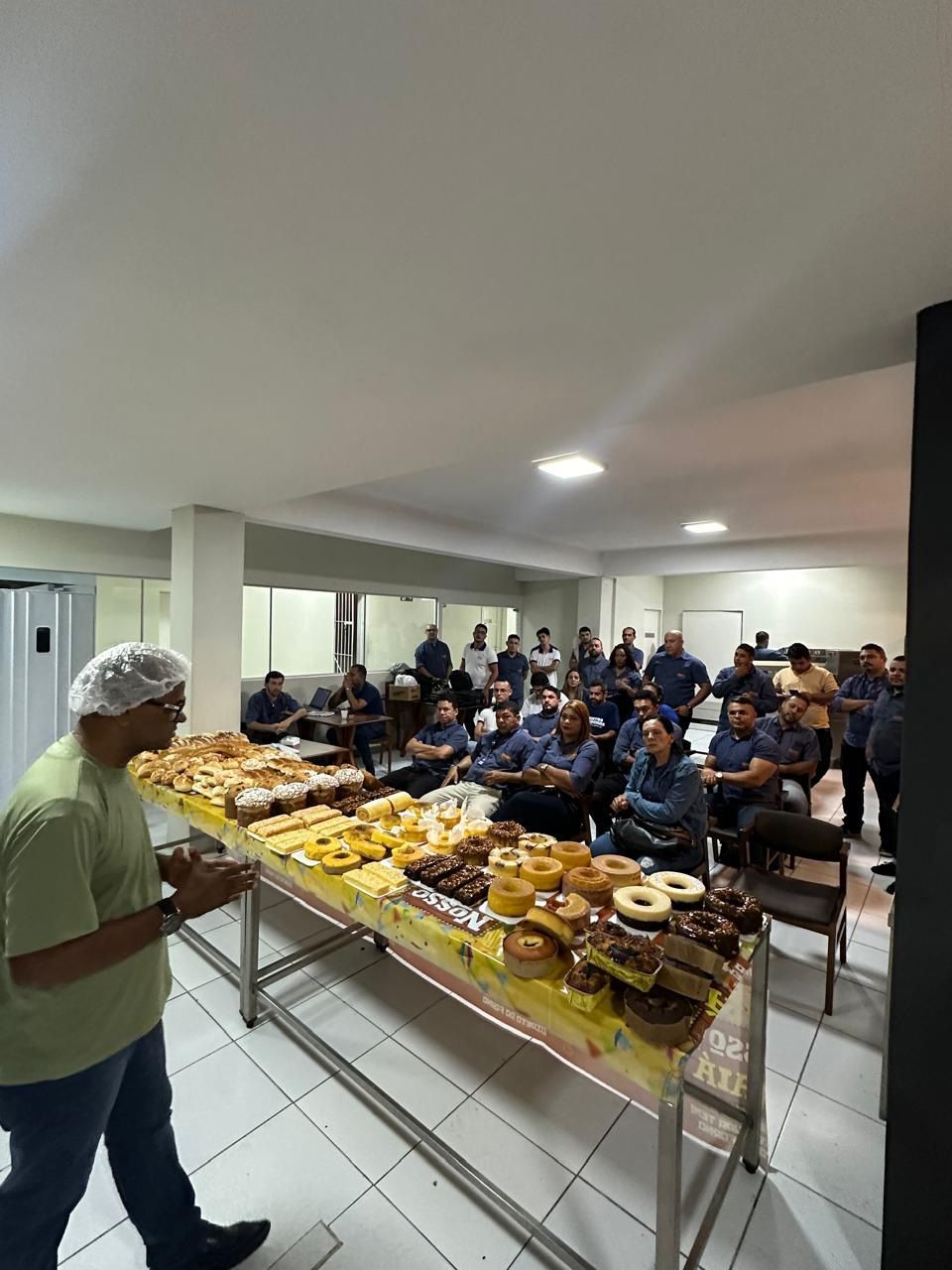 Um homem está de pé em frente a uma mesa cheia de comida.