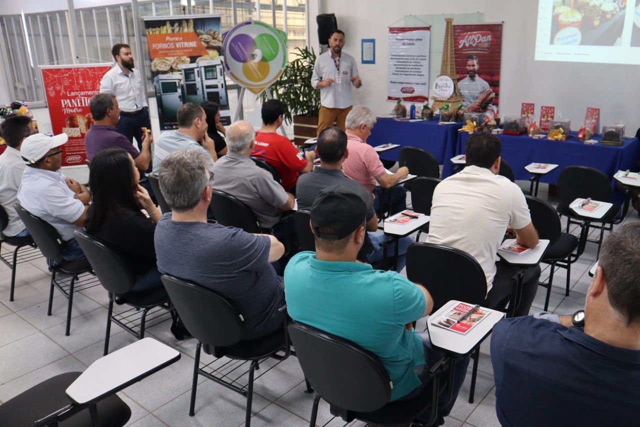 Um grupo de pessoas está sentado em cadeiras assistindo a uma apresentação