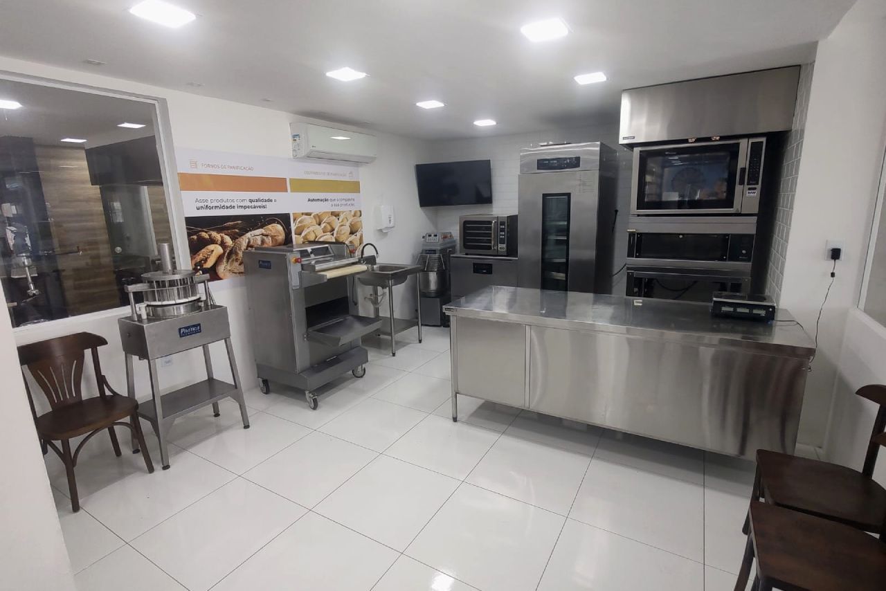 Uma cozinha com muitos eletrodomésticos e cadeiras de aço inoxidável.