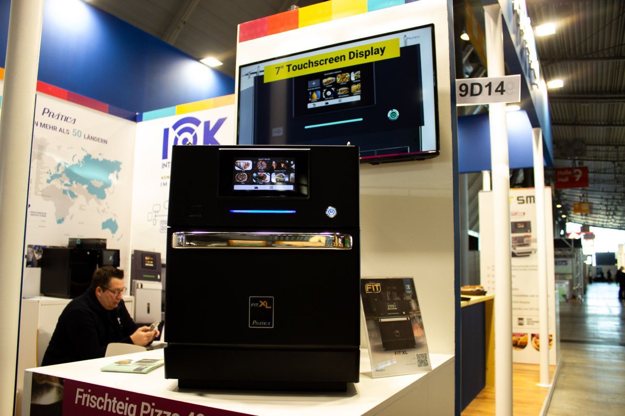 Um homem sentado em uma mesa em frente a uma placa que diz 9d14
