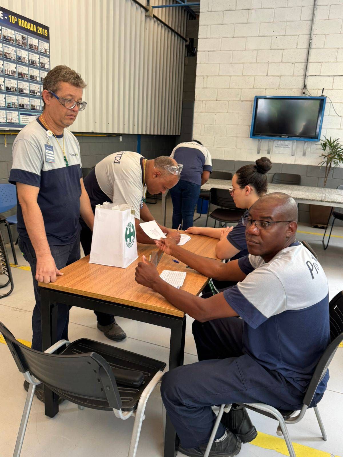 Um grupo de pessoas está sentado em mesas em uma sala.