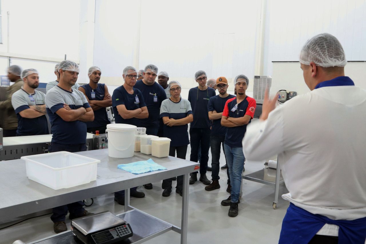 Um homem está fazendo uma apresentação para um grupo de pessoas em uma cozinha.
