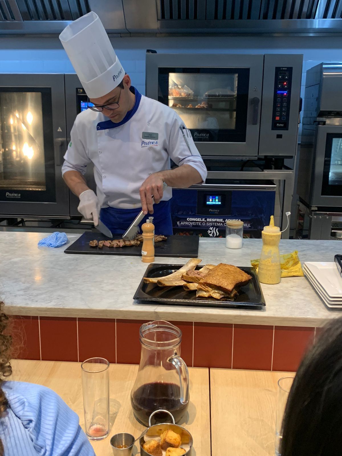 Um homem com chapéu de chef está cozinhando comida em uma cozinha.