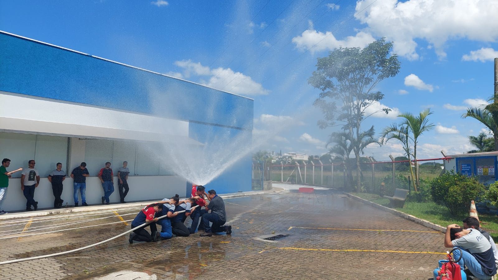 Um grupo de pessoas está jogando água em um incêndio em frente a um prédio.