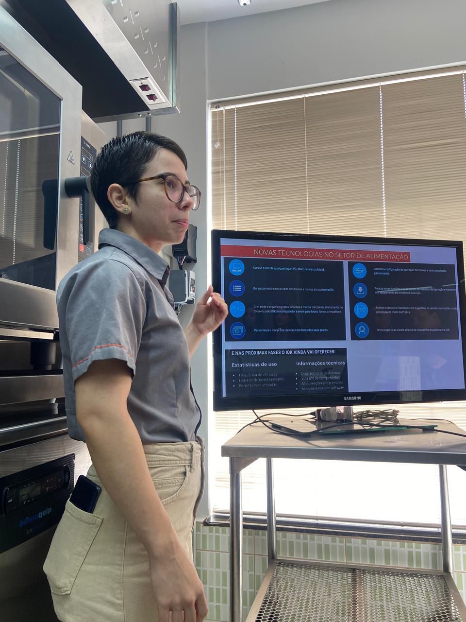 Uma mulher está fazendo uma apresentação em frente a uma tela de computador.