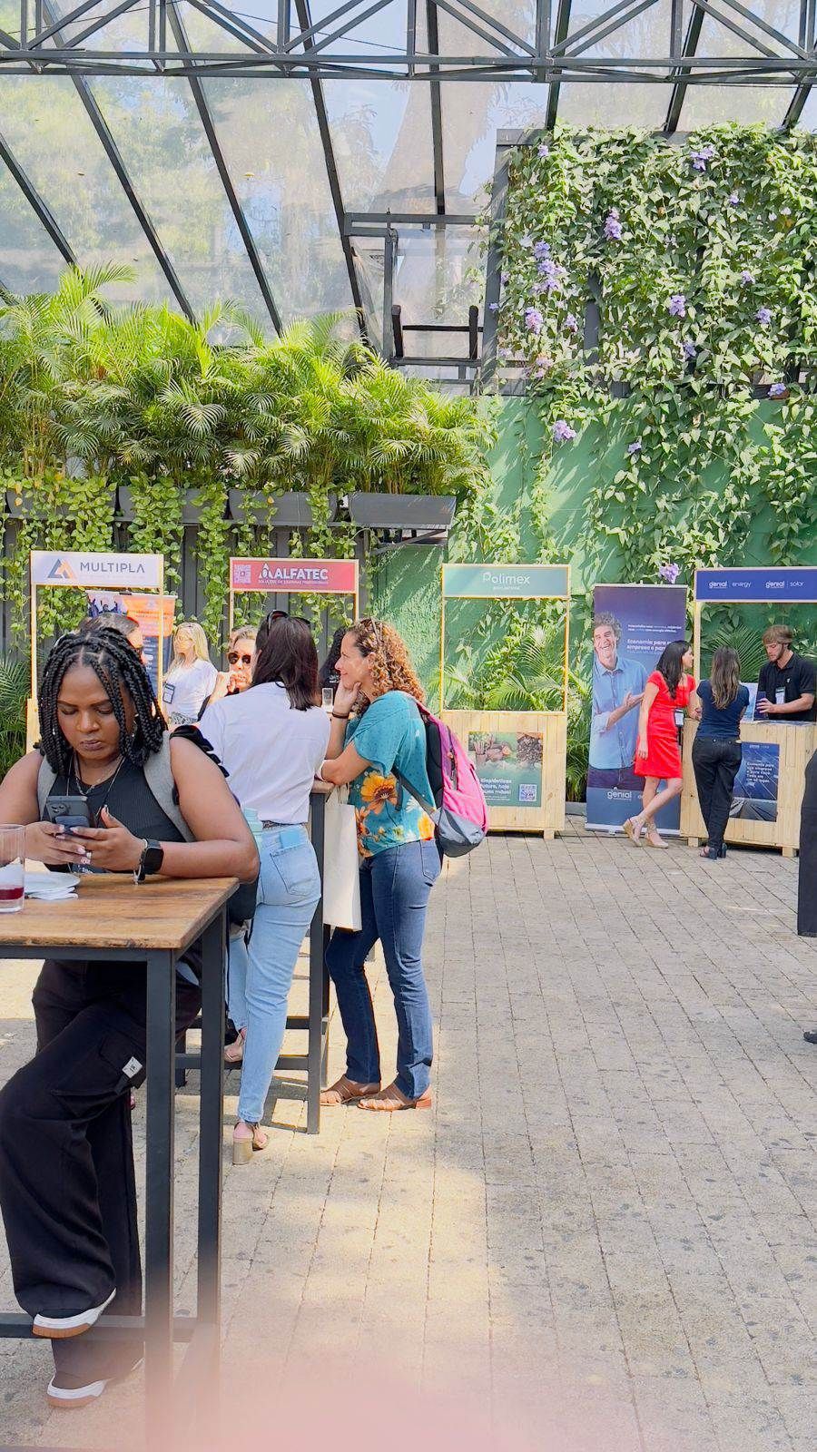 Uma mulher está sentada à mesa em uma estufa olhando para seu telefone.