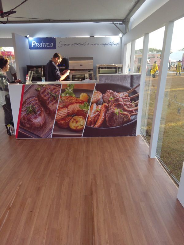 Um homem está sentado em um balcão em frente a uma exposição de comida.