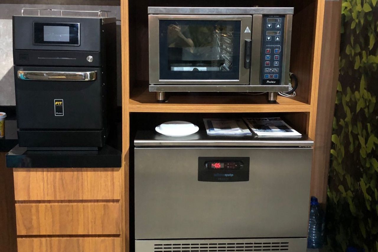 Um forno combinado está em cima de uma prateleira de madeira.