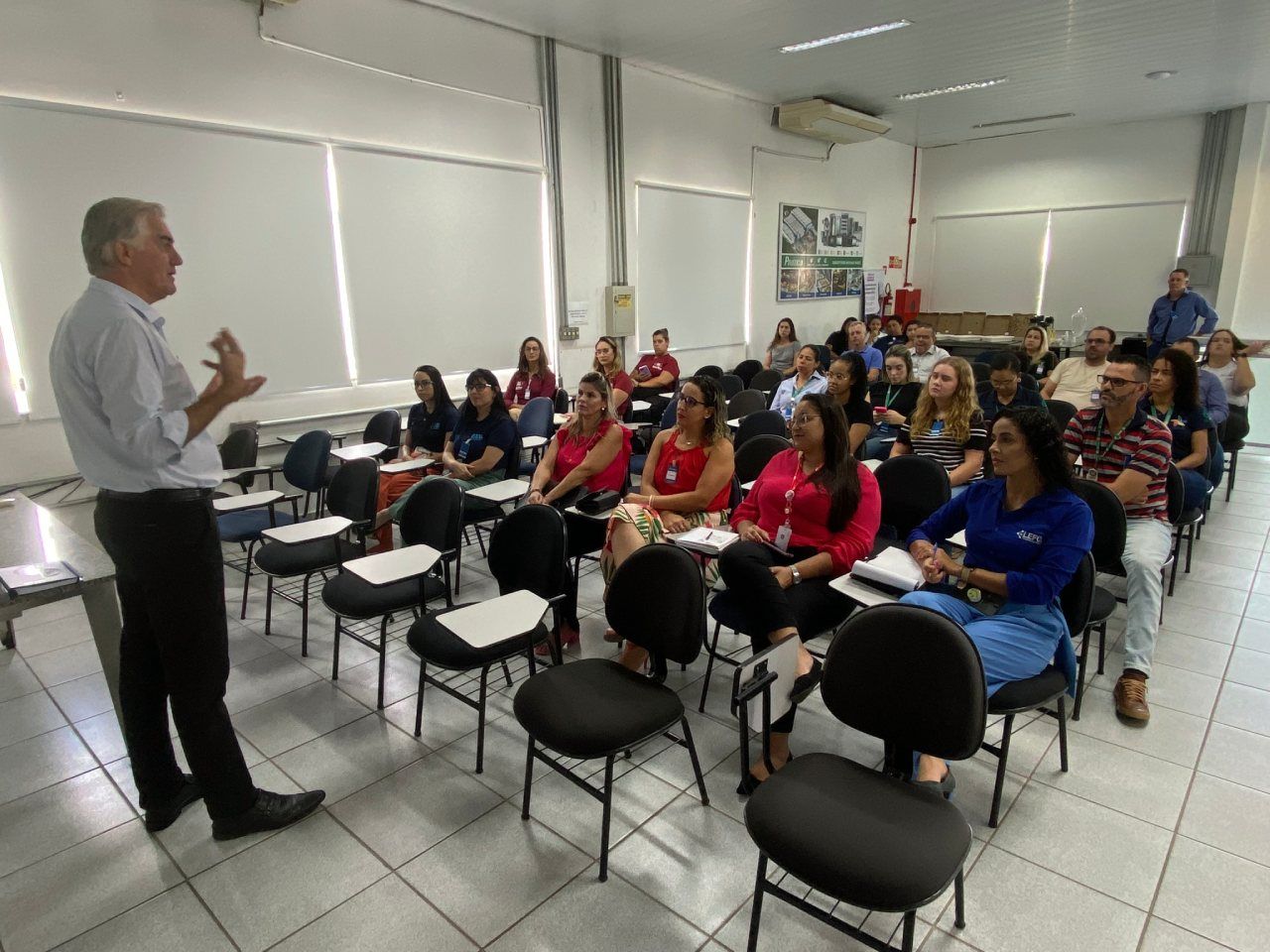 Um homem está fazendo uma apresentação para um grupo de pessoas sentadas em cadeiras.