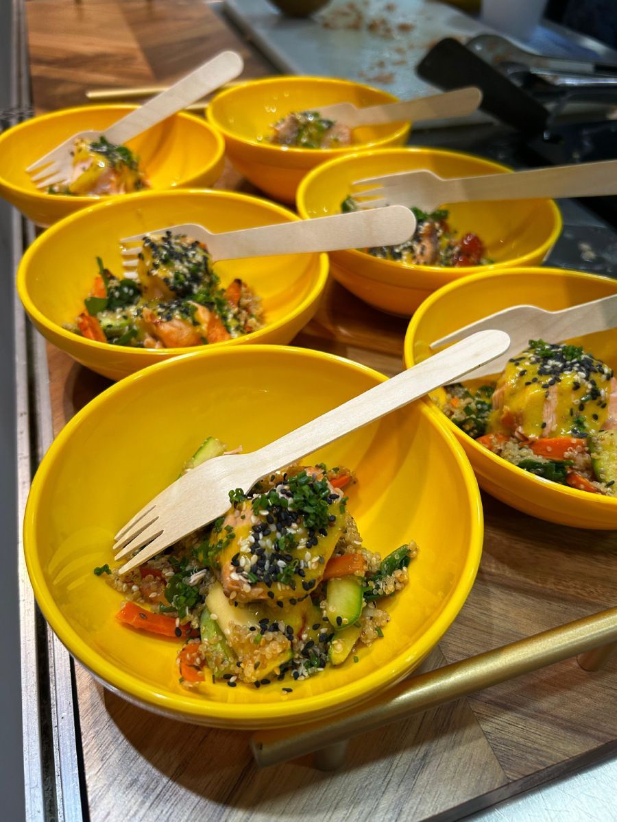 Um monte de tigelas amarelas cheias de comida e garfos de madeira