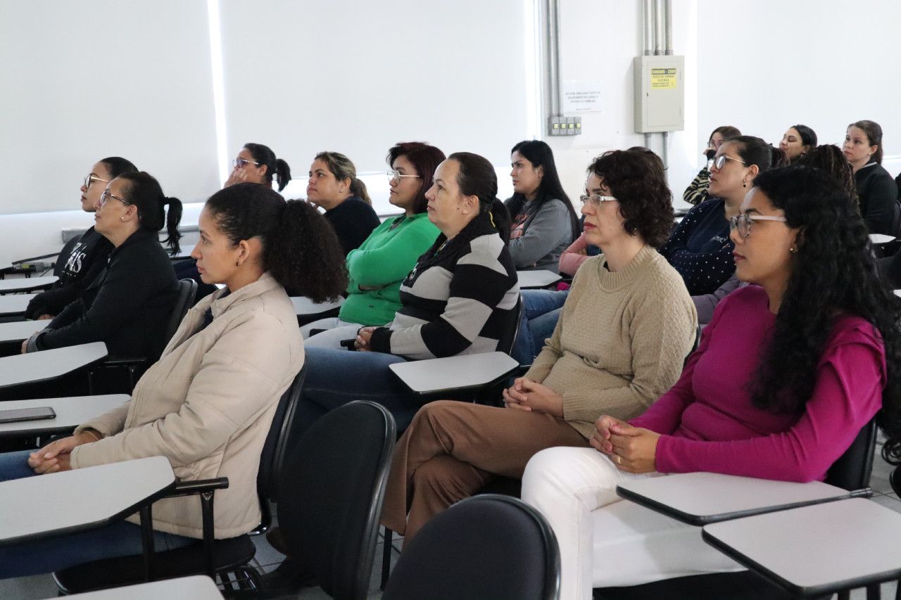 Um grupo de pessoas está sentado em carteiras em uma sala de aula.