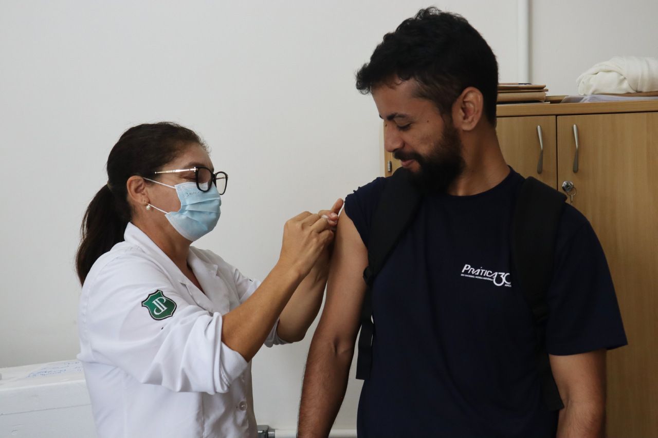 Uma mulher usando uma máscara está dando uma vacina a um homem