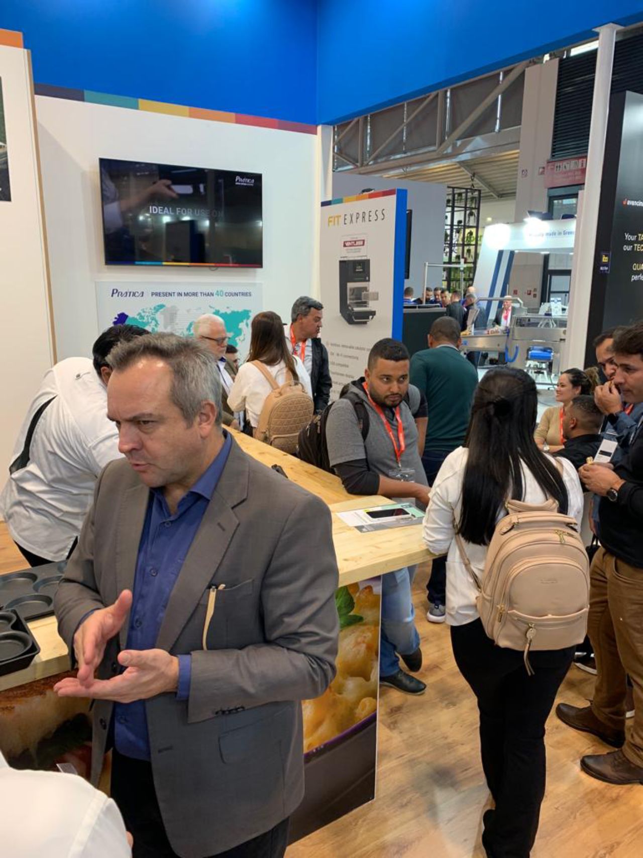 Um grupo de pessoas está em pé ao redor de uma mesa em uma sala.