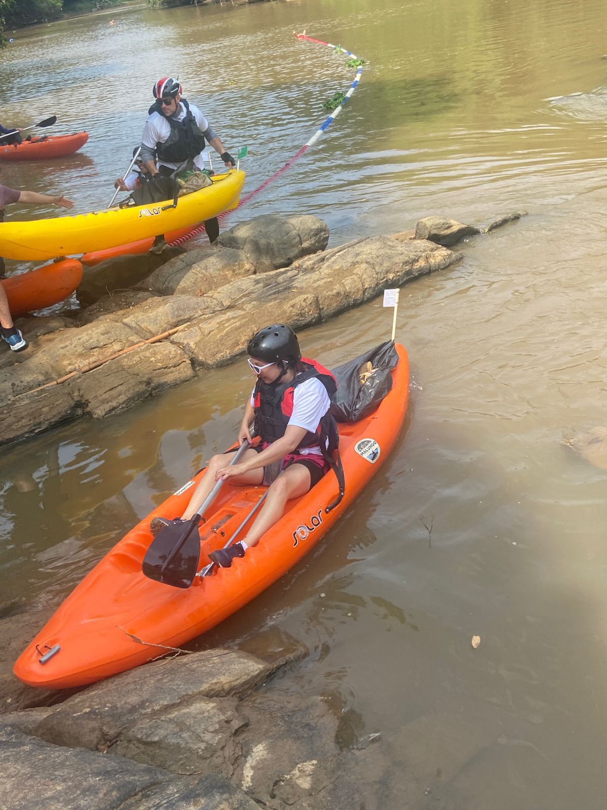 Um homem está sentado em um caiaque laranja em um rio.