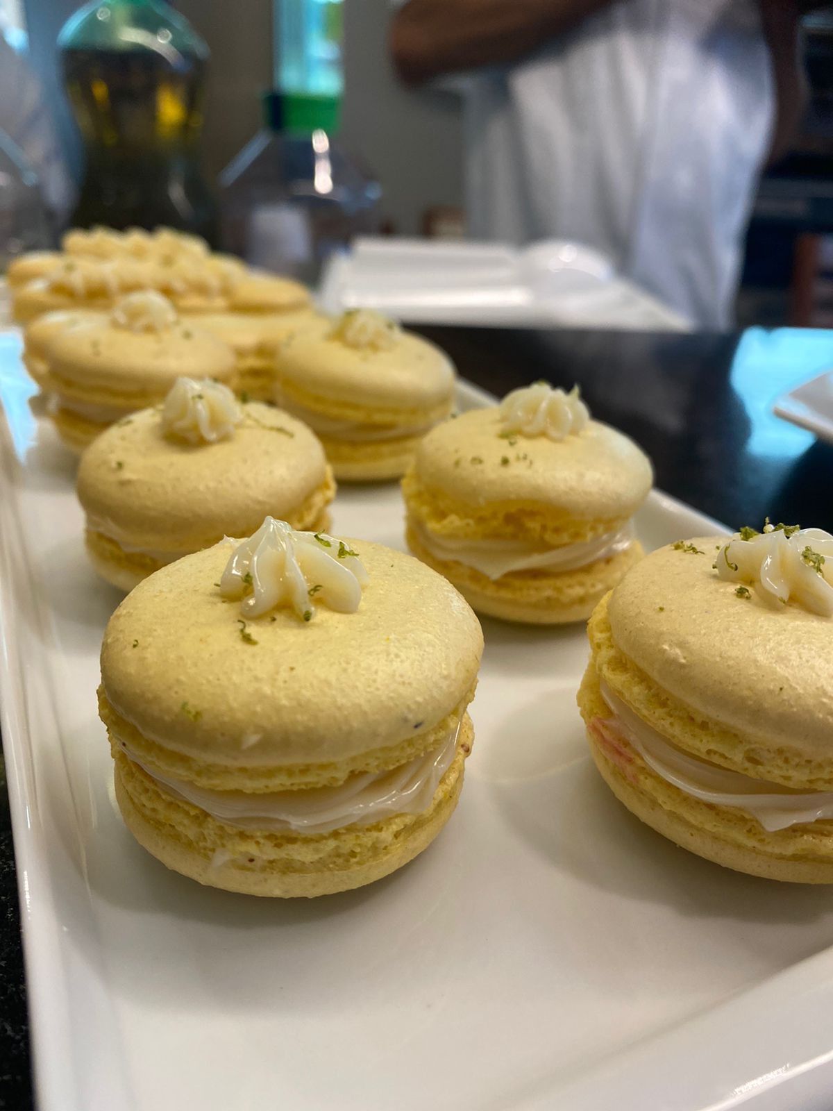 Uma bandeja branca cheia de macarons amarelos sobre uma mesa.
