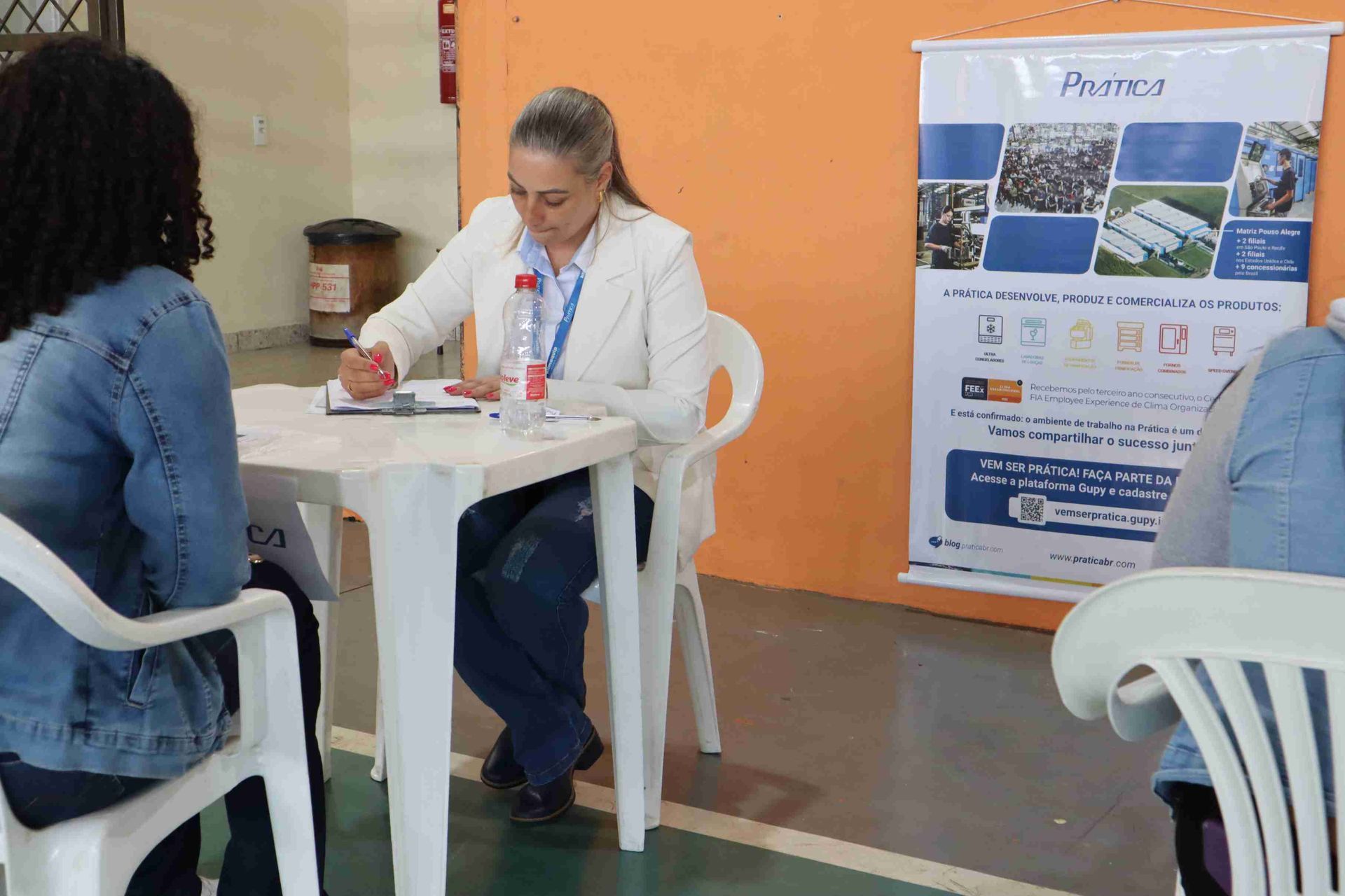 Uma mulher está sentada à mesa conversando com duas mulheres.