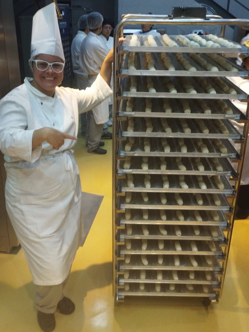 Uma mulher em uniforme de chef está apontando para uma prateleira de comida