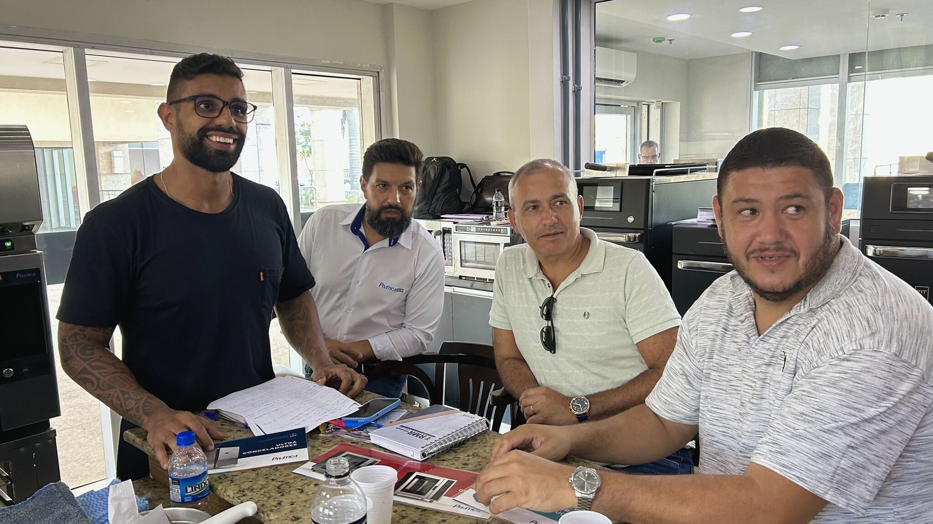 Um grupo de homens está sentado ao redor de uma mesa em um escritório.