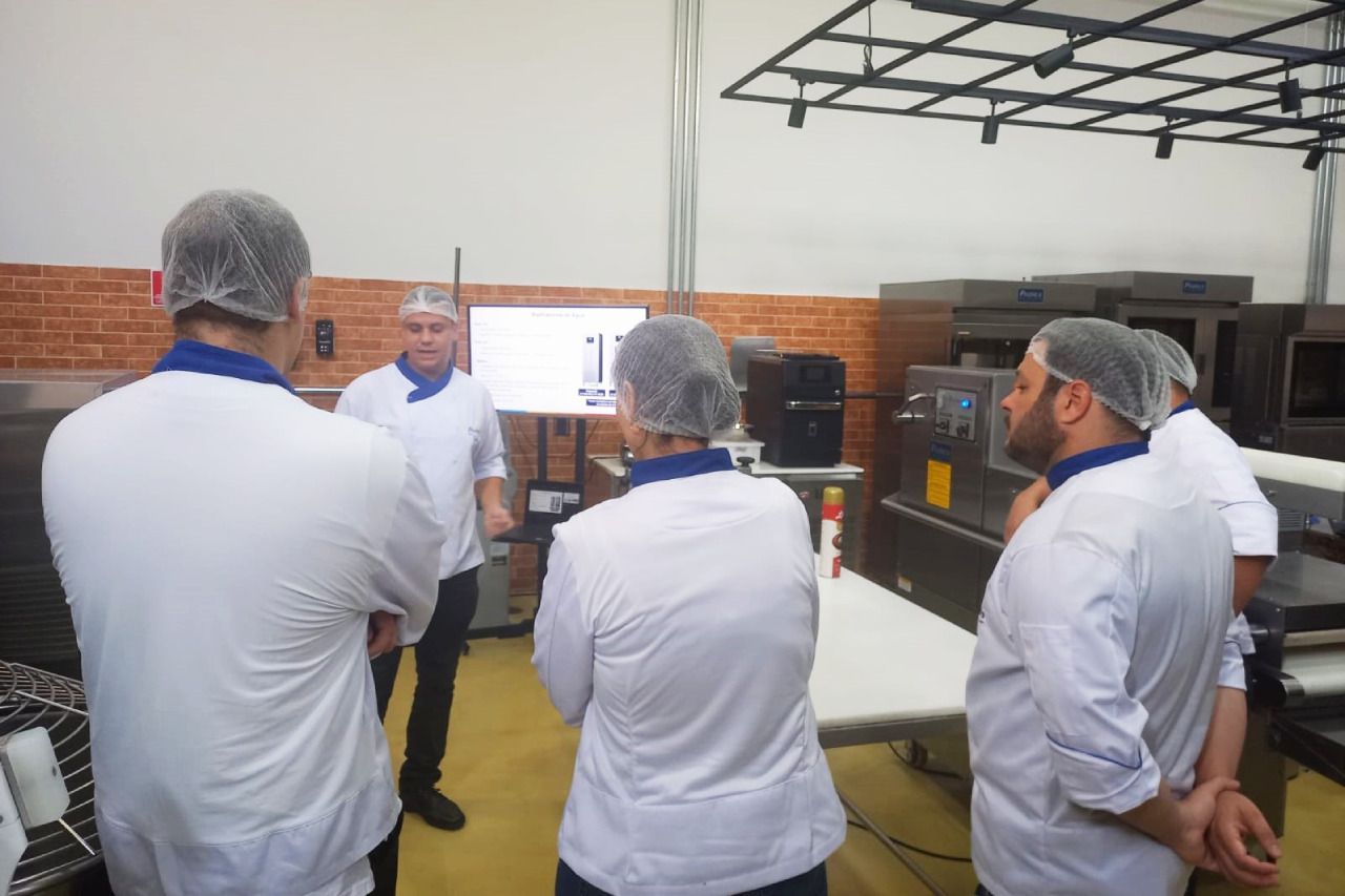 Um grupo de chefs estão em uma cozinha conversando entre si.