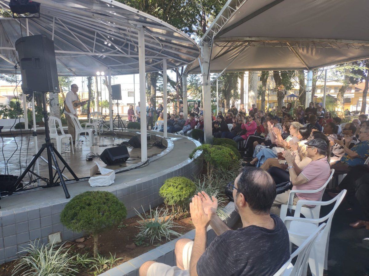 Um grupo de pessoas está sentado sob uma barraca em um parque.