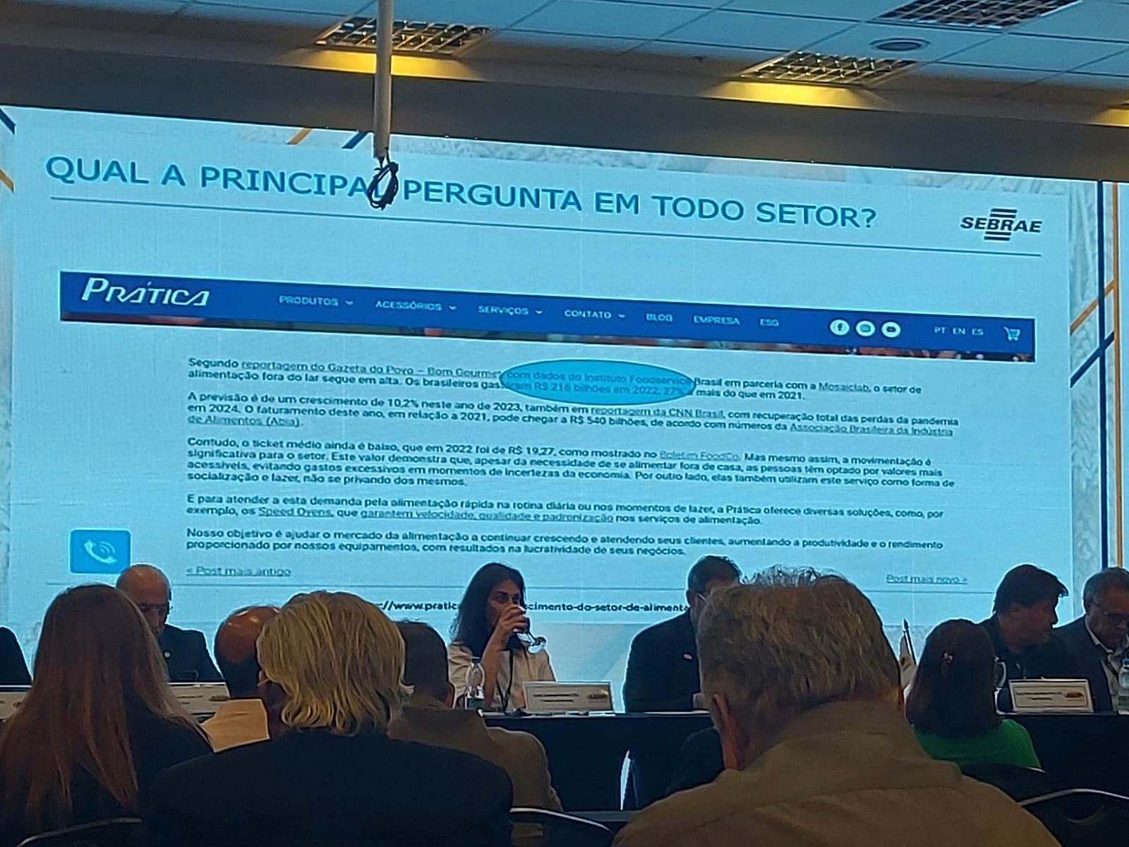 Um grupo de pessoas está sentado em frente a uma tela grande que diz qual a principal pergunta em todo setor