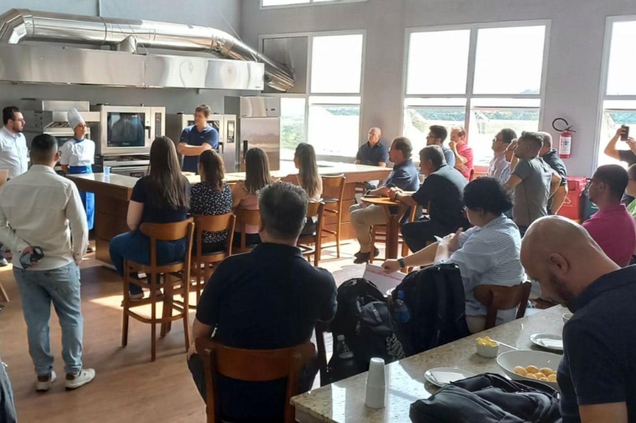 Um grupo de pessoas está sentado em mesas em uma cozinha.
