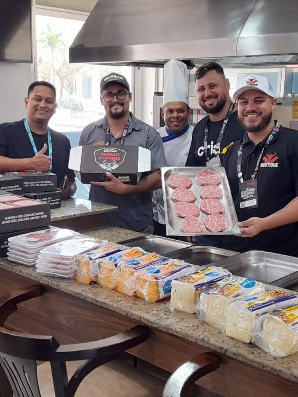 Um grupo de homens está em pé ao redor de um balcão segurando bandejas de comida.