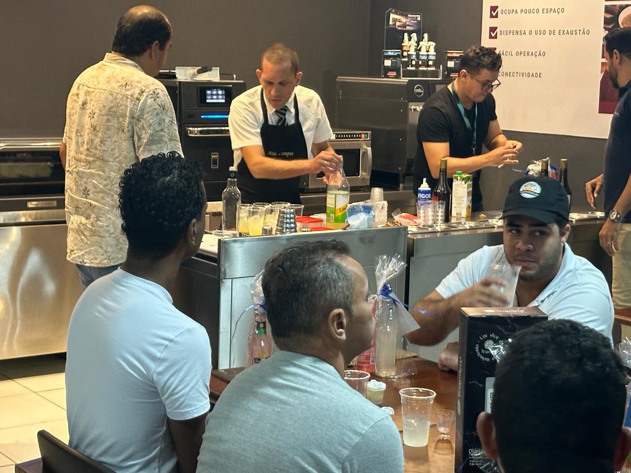 Um grupo de homens está sentado ao redor de uma mesa na cozinha.