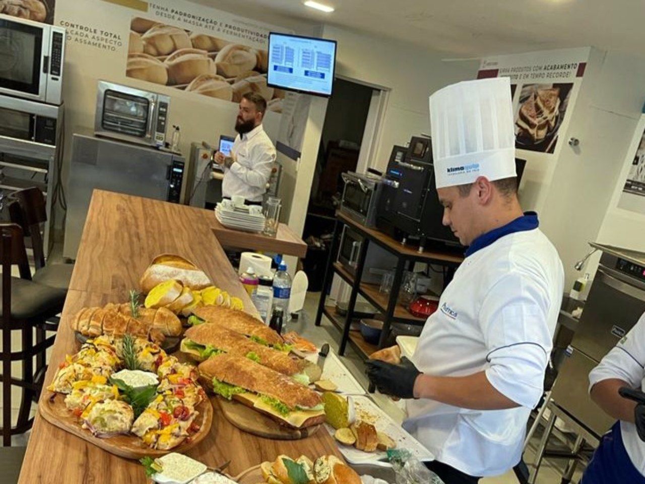 Um homem com chapéu de chef está preparando comida em uma mesa.