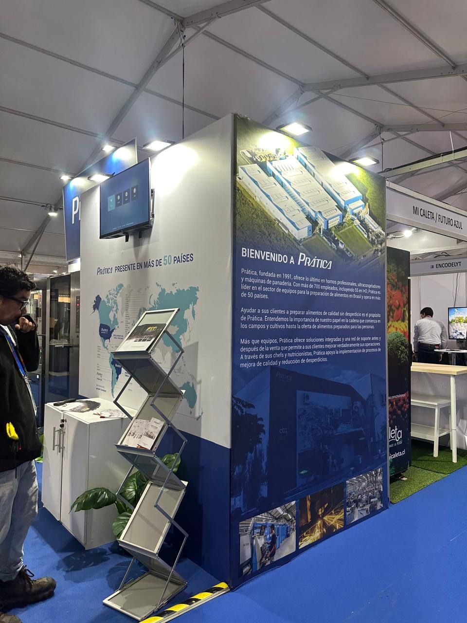 Um homem está parado em frente a um estande em uma convenção.