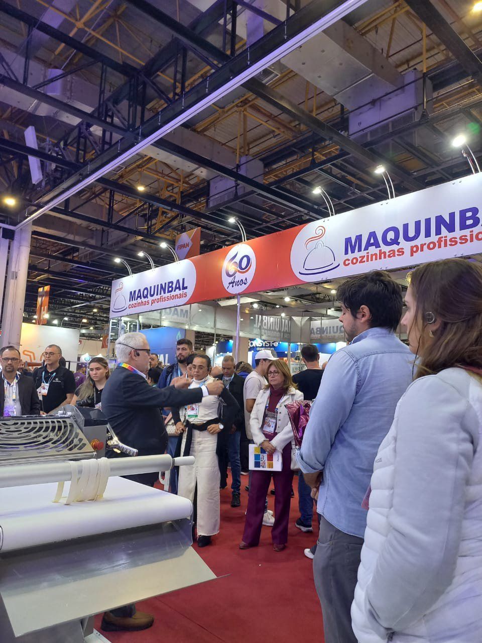 Um grupo de pessoas está em frente a uma placa que diz maquinb