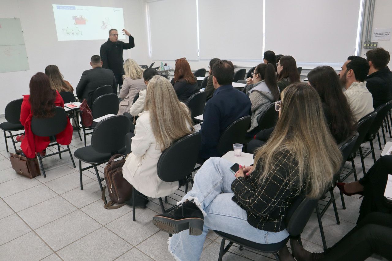 Um grupo de pessoas está sentado em cadeiras em frente a uma tela de projetor.