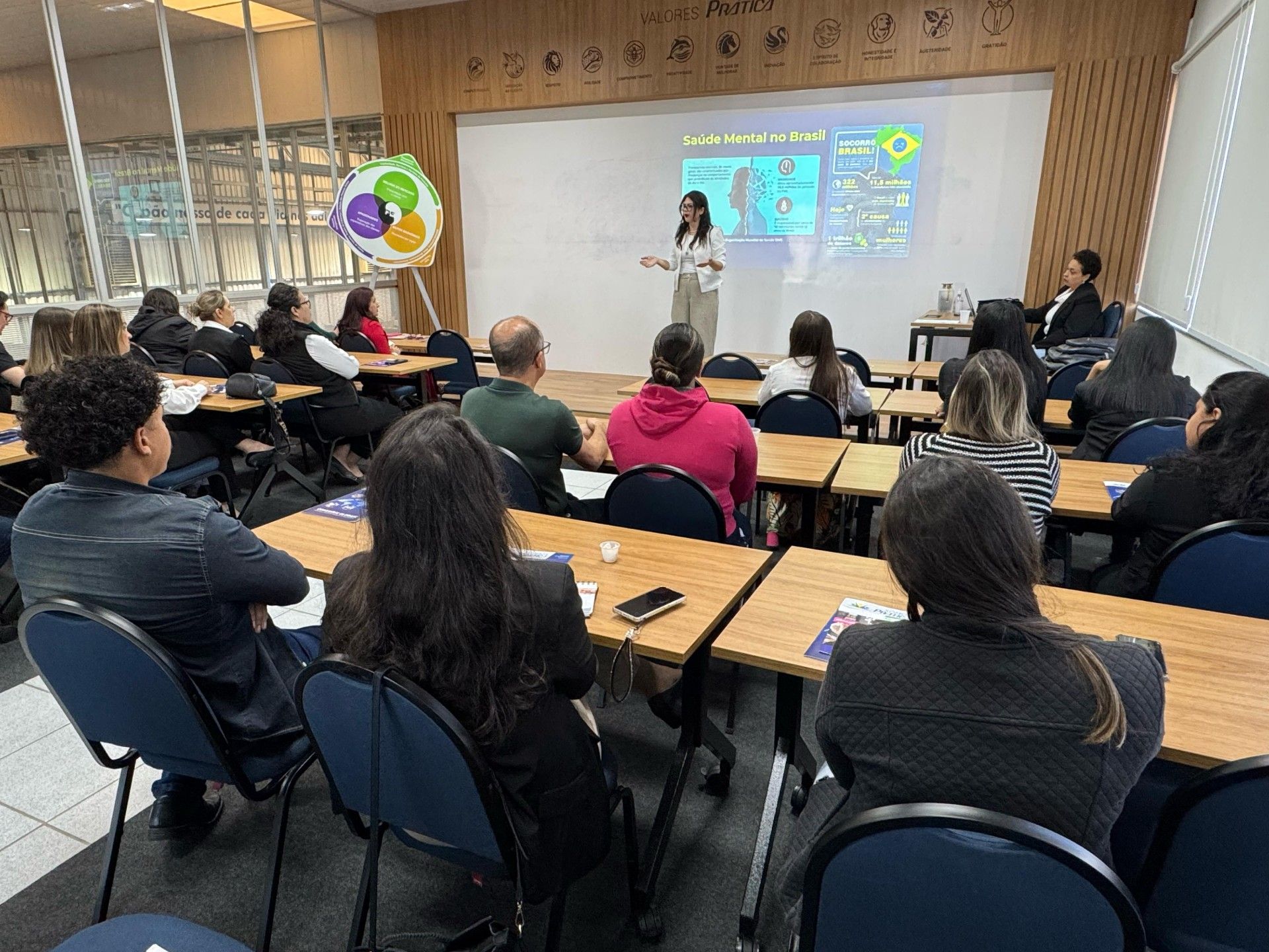 Uma mulher está fazendo uma apresentação para um grupo de pessoas em uma sala de aula.
