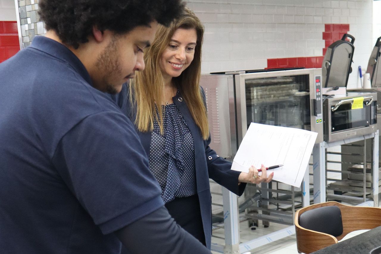 Um homem e uma mulher estão olhando um pedaço de papel na cozinha.