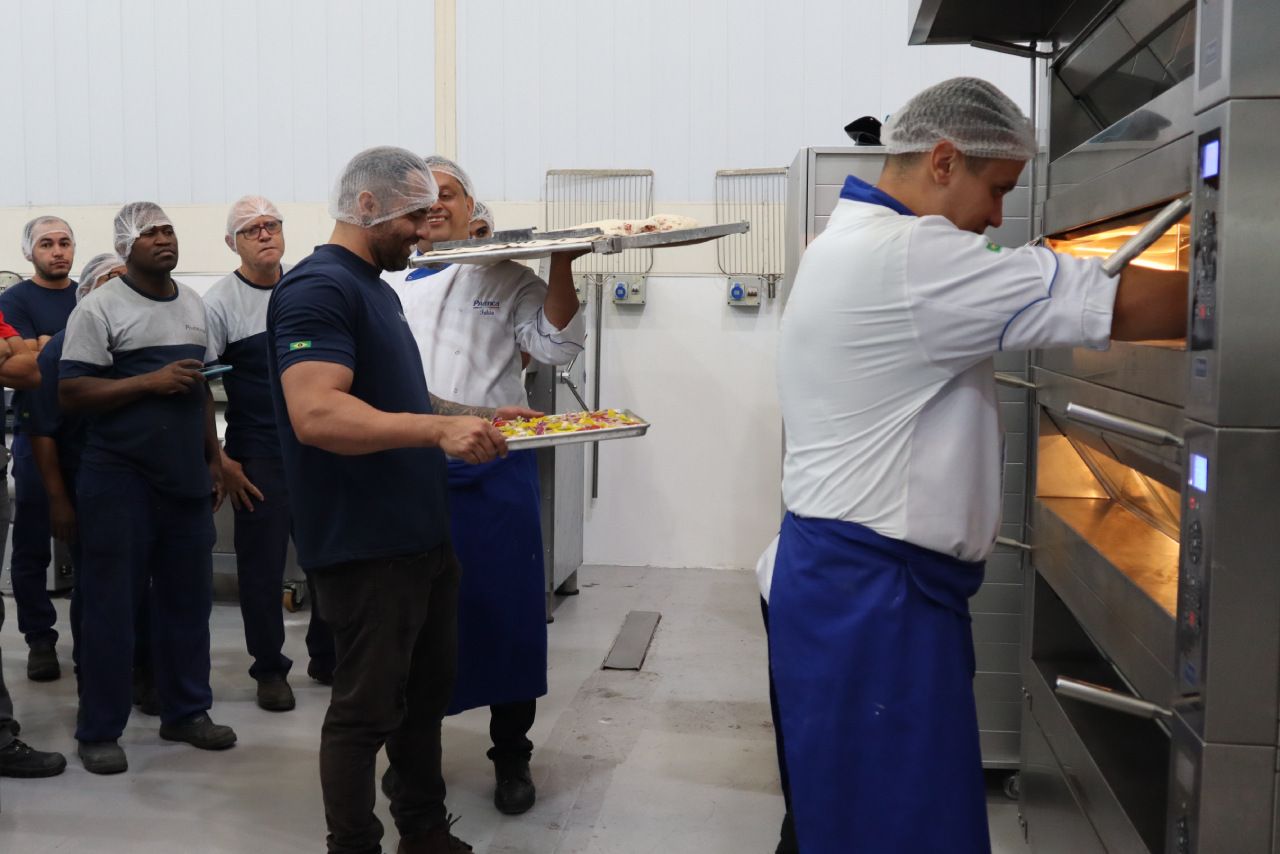 Um grupo de homens está em uma cozinha segurando bandejas de comida.