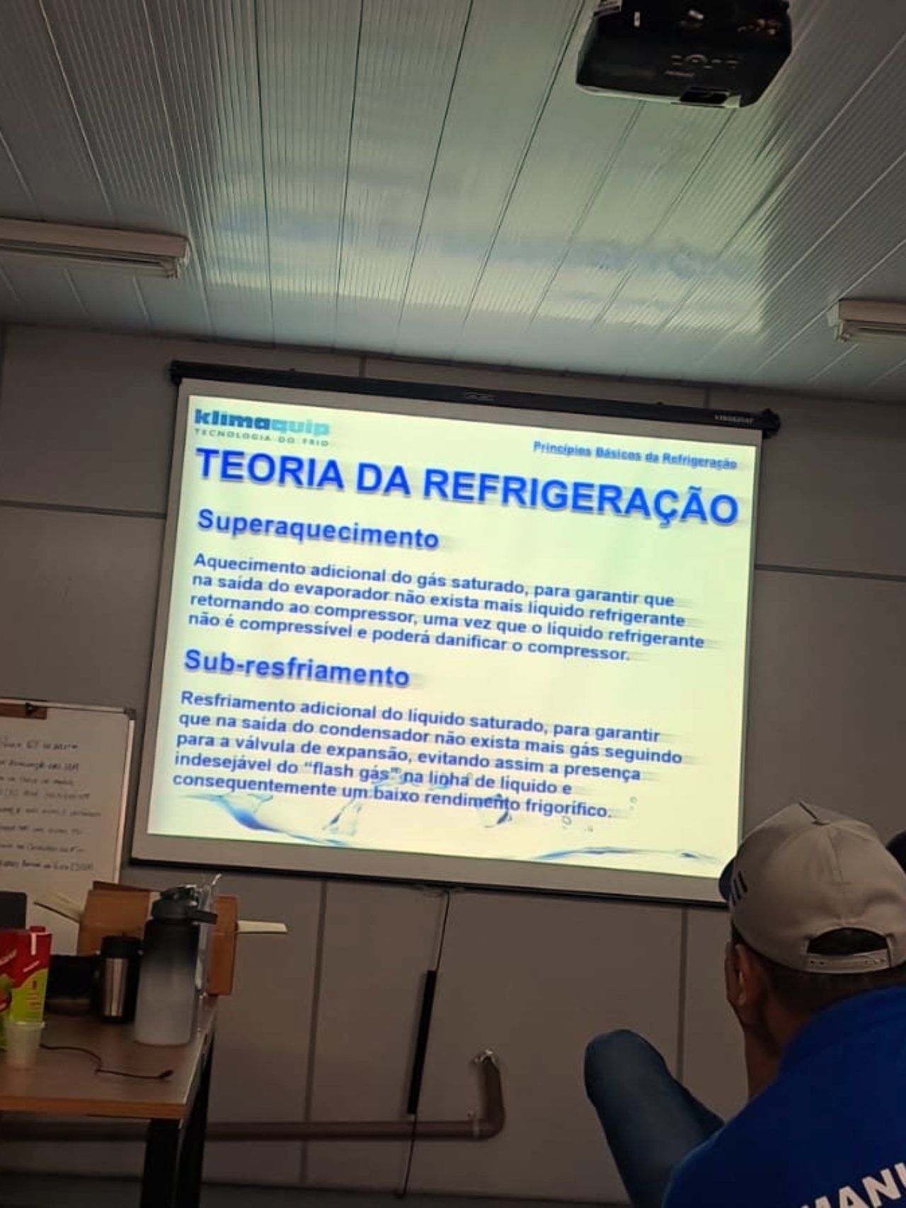 Um homem senta-se em frente a uma tela que diz teoria da refrigeração