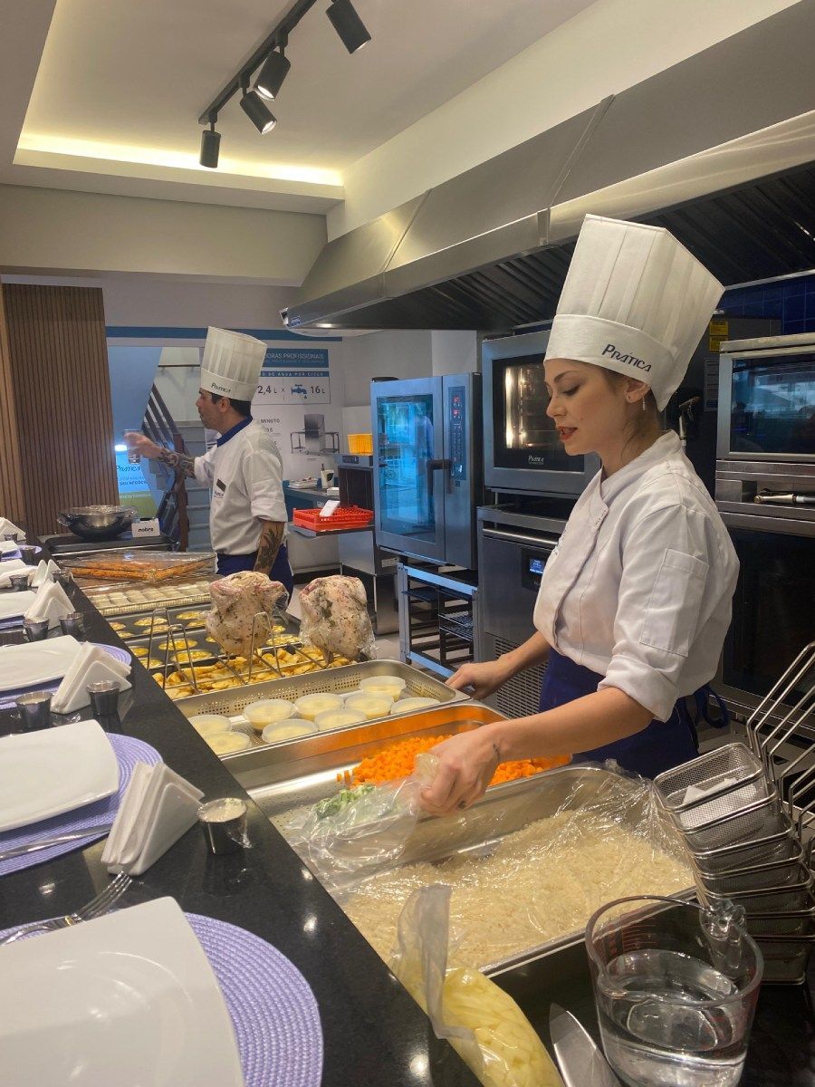 Uma mulher com chapéu de chef está preparando comida na cozinha.