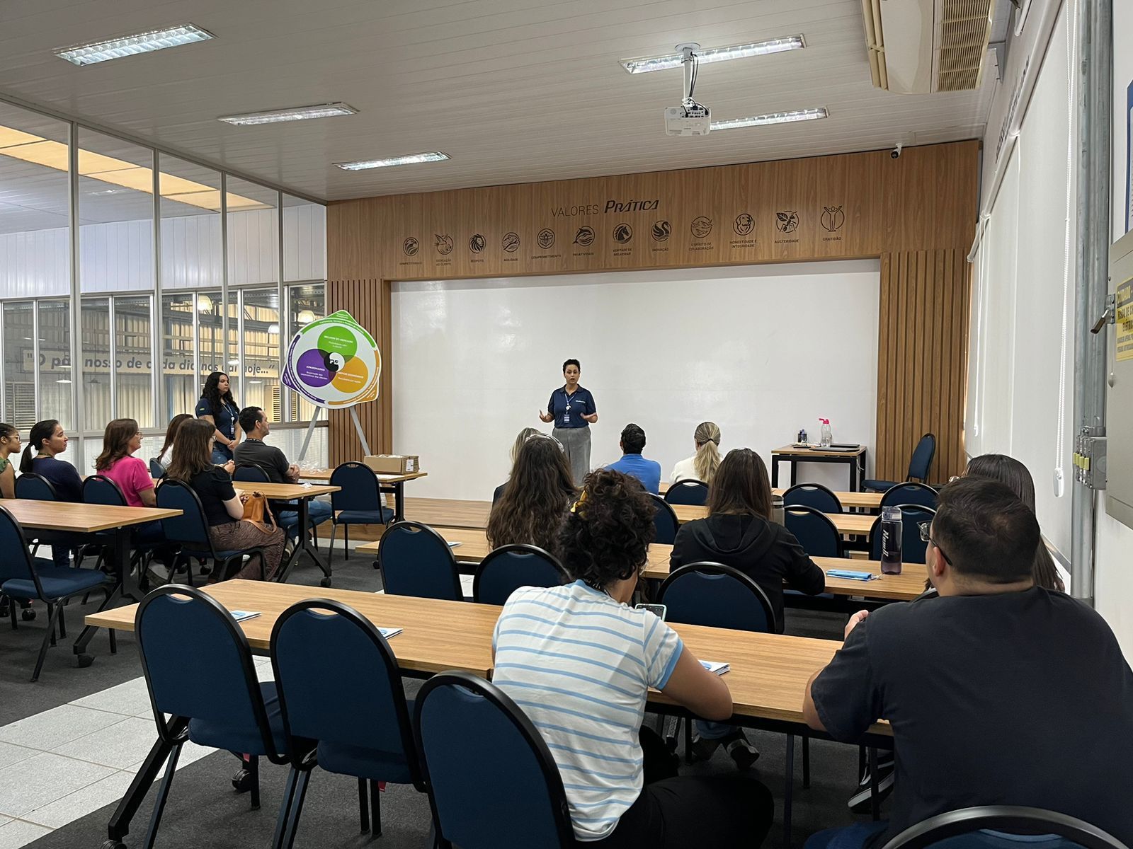 Um grupo de pessoas está sentado em mesas em uma sala de aula.