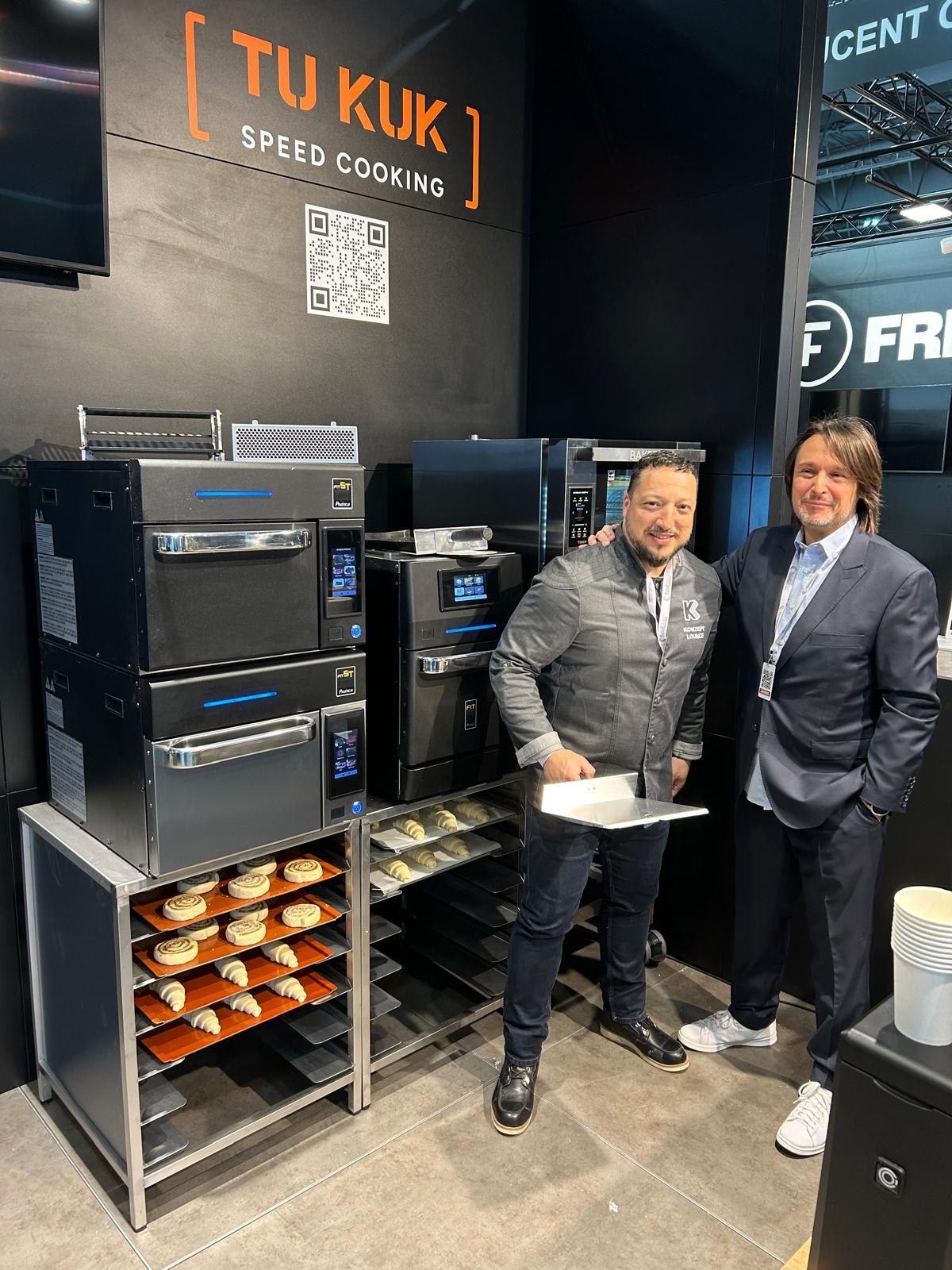 Dois homens estão em frente a uma exposição de equipamentos de cozinha.