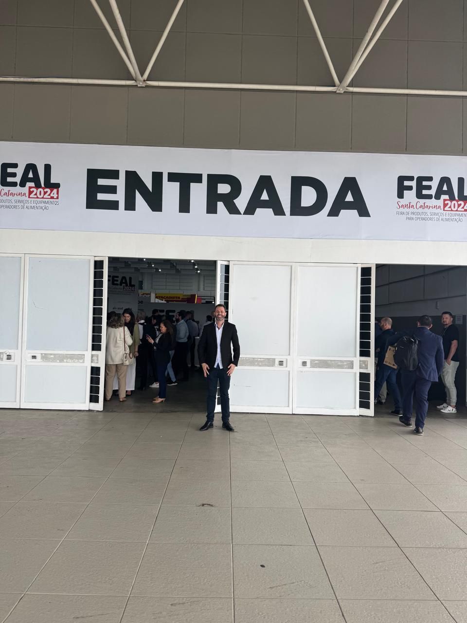 Um homem de terno está em frente a uma placa que diz entrada
